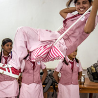 Girls in school uniforms, one on a swing.