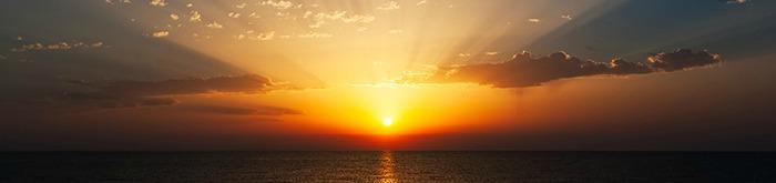 Sun rising on the ocean's distant  horizon
