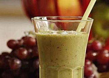 Green smoothie surrounded by grapes