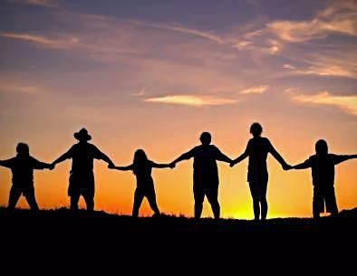 People holding hands facing the sunrise
