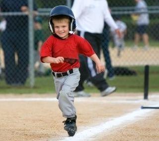 Little boy running to third base from home plate