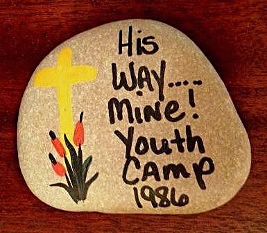 A small river rock with a painted yellow cross, red flowers, and the words His Way...Mine!
