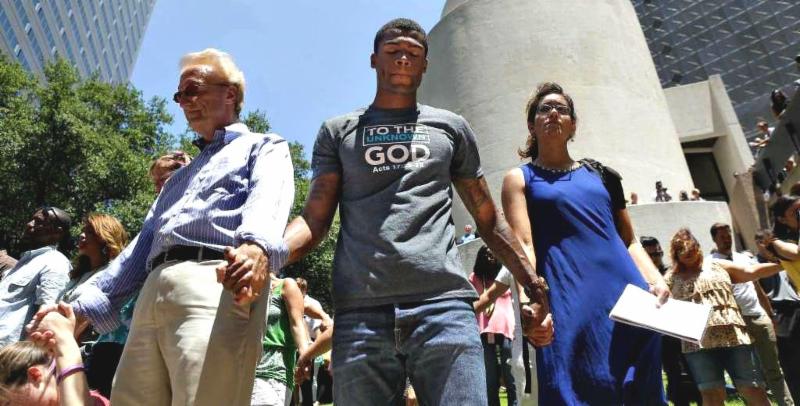 People of different races, ages, and gender, united as they hold hand and pray.