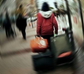 Homeless woman wandering the streets, bundled up, pulling suitcases