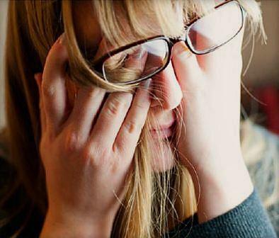 A stressed woman, her hands rubbing her face