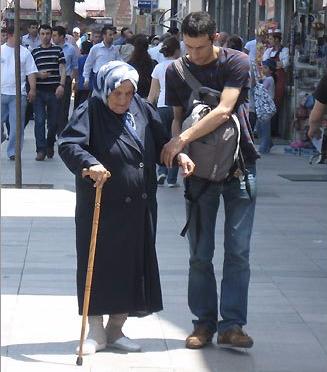 A man helping an elderly lady cross a busy street