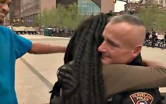 Black woman hugging a crying white police office.