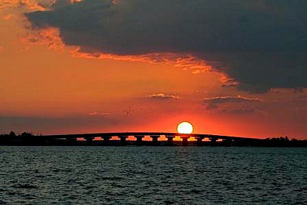 Sunset beyond an ocean bridge