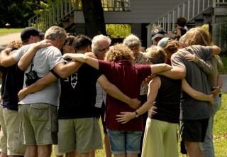 Many people in a circle, their arms around each other