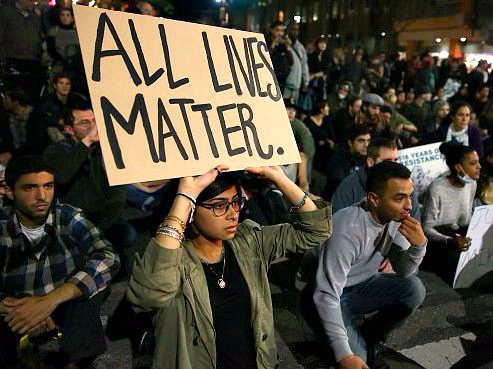 A demonstrator holding a sign that reads, ALL LIVES MATTER