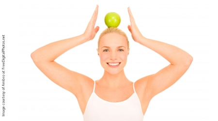 Image of a smiling woman balancing an apple on her head