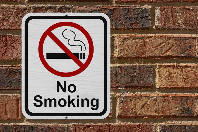 No Smoking Sign Red and White sign with words No Smoking and cigarette symbol on a brick wall