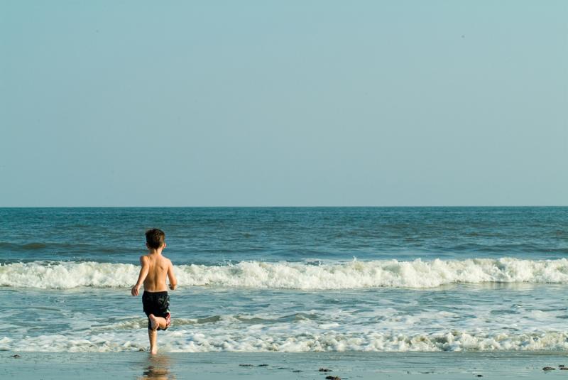 Young boy running into the ocean.