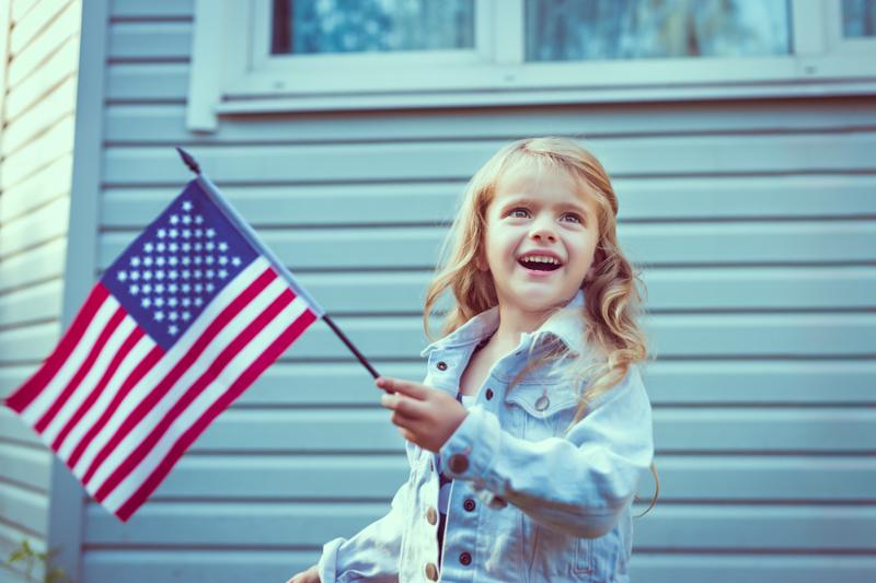 Pretty little girl with long curly blond hair smiling and waving american flag. Independence Day Flag Day concept. Vintage and retro colors. Instagram filters