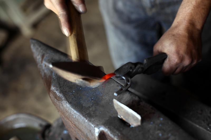 Color shot with a blacksmith working on a horse shoe on an anvil.