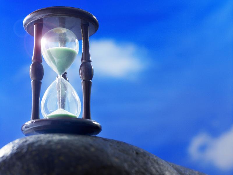 hour glass on the rock with blue sky as back ground