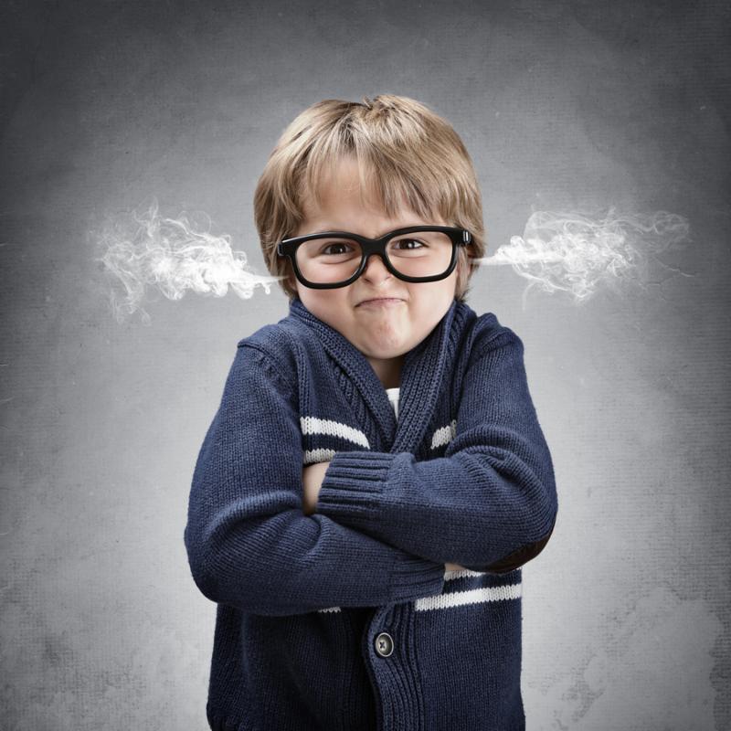 Upset and angry boy with steam coming from his ears and arms folded concept for anger, frustration and mischief