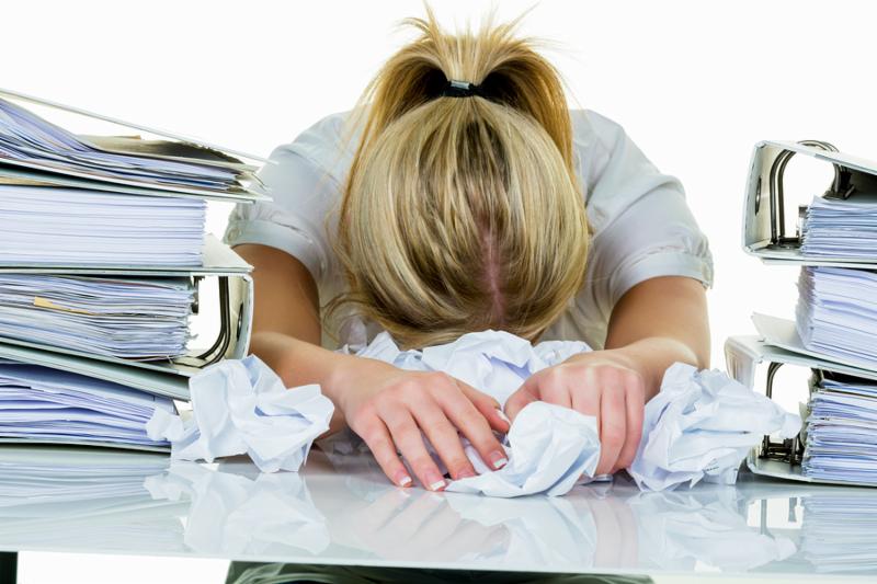a young woman desperately in office between many file folders and crumpled papier.symbolfoto for stress, burnout and overwork.