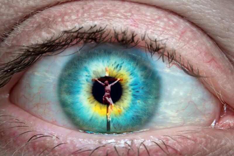 Close up of eye with Jesus Christ on the cross reflected in it