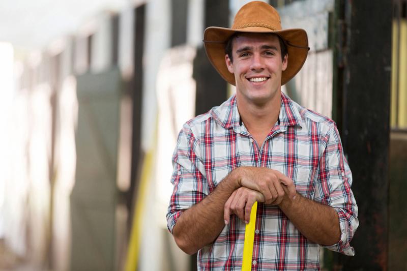portrait of happy horse breeder inside stable