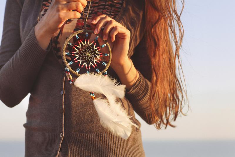 Brunette woman with long hair holding dream catcher in her hands