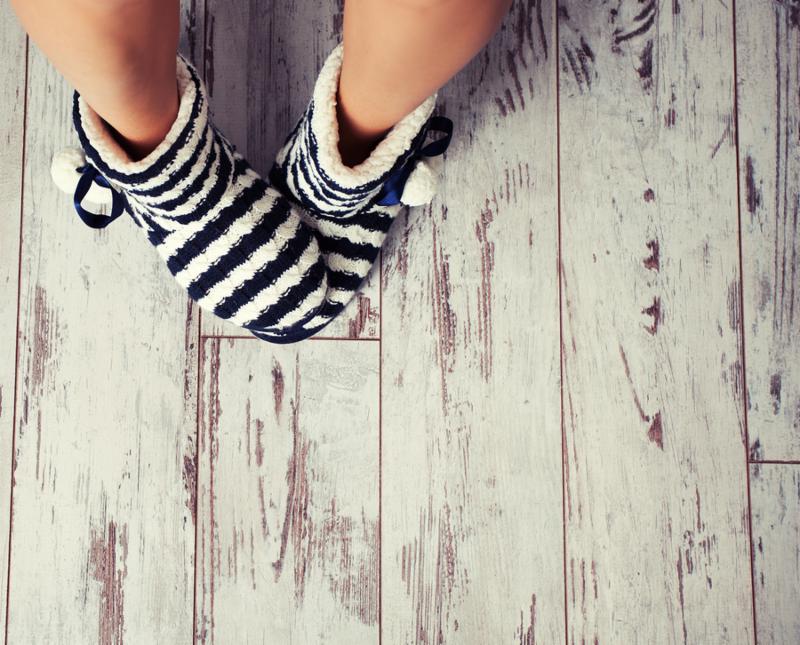 Warm slippers on the background old white floor. Homeliness. 
