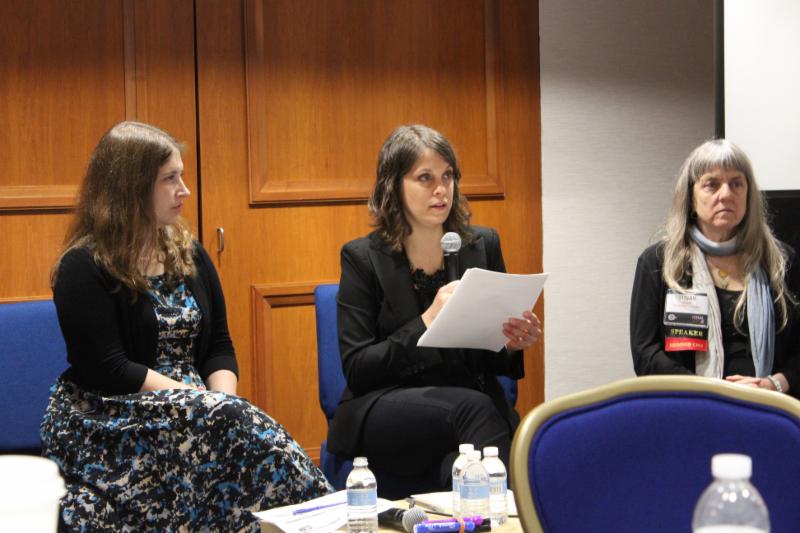Lisa Adams sitting and speaking alongside two presenters during a conference
