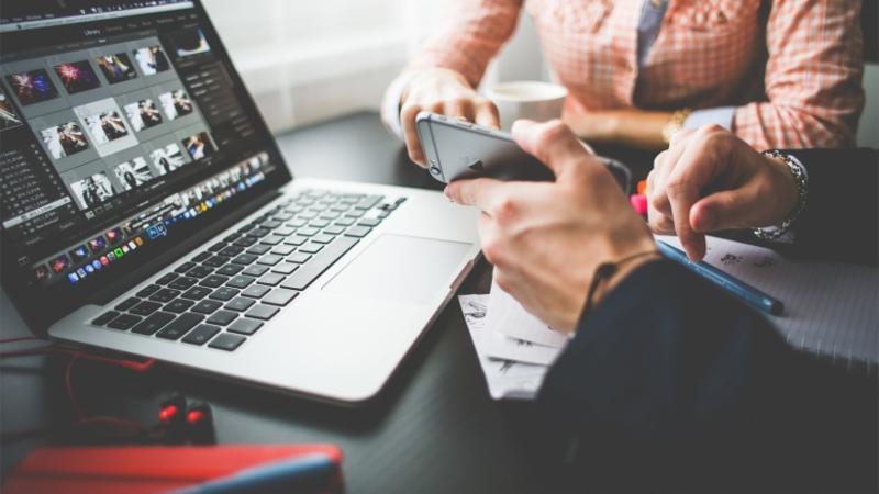 Two people planning marketing strategy with laptop and phone