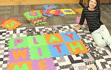 Child with floor puzzle spelling out Play With Me