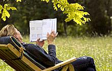 Adult reading outdoors in lawn chair