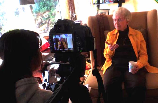 students videotaping senior in a chair