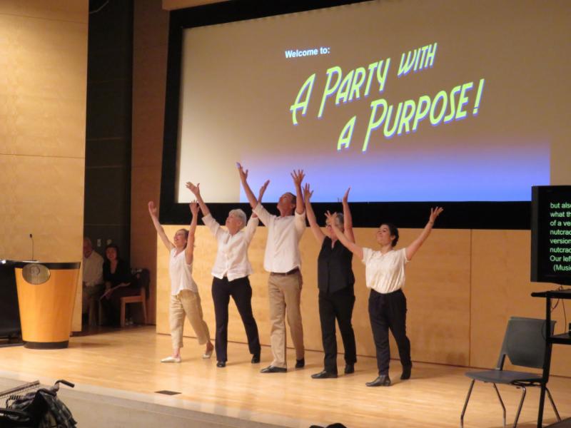 dancers in front of a large screen that says Party with a Purpose