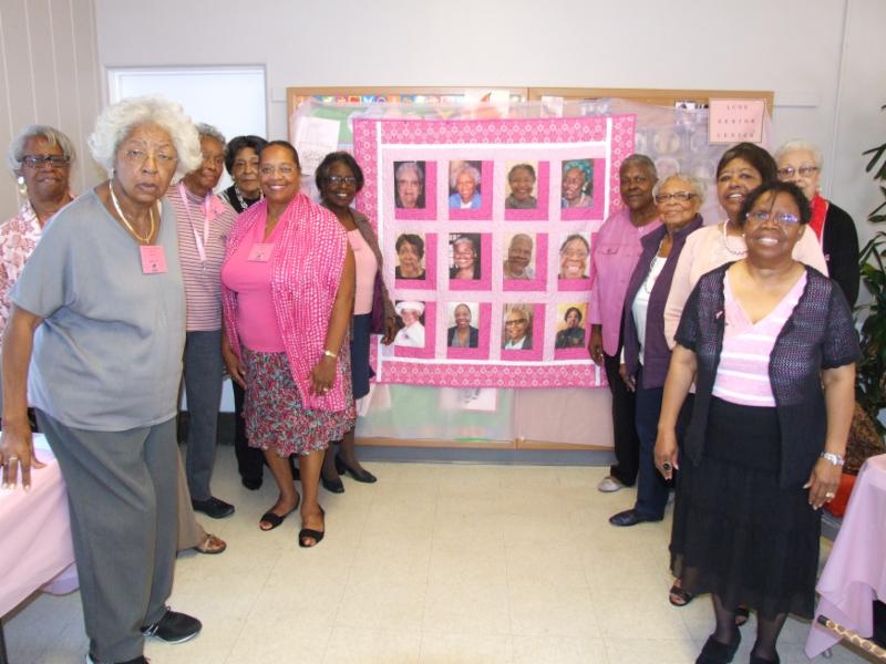 ladies in front of quilt with their picture