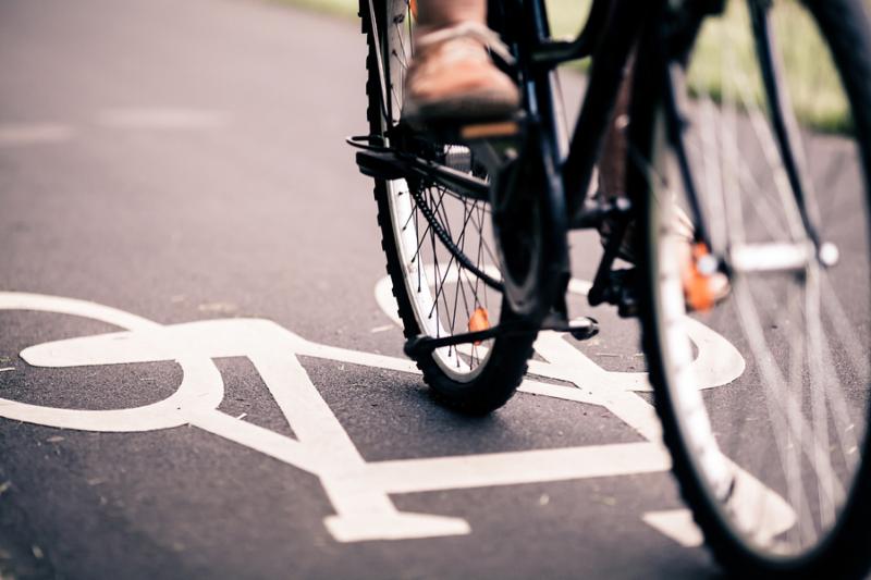 City bicycle riding on bike path alternative ecological transportation. Commute on bicycle in urban environment asphalt gray bike lane with bicycle markings