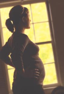 Sillouetted pregnant woman at a window