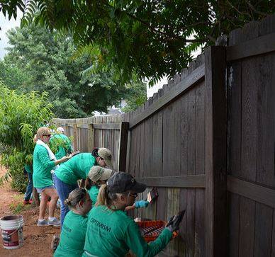 Employees painting a fence