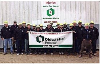 Employees in hardhats  standing with banner