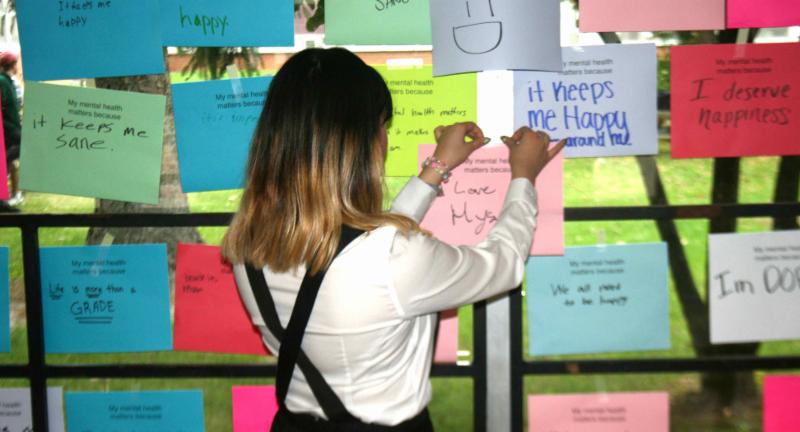 female high school student taping a sign to the wall