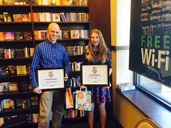 teacher and student holding award certificates in award ceremony at bookstore