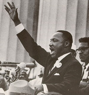 Martin Luther King Jr boldly speaking with his hand in the air