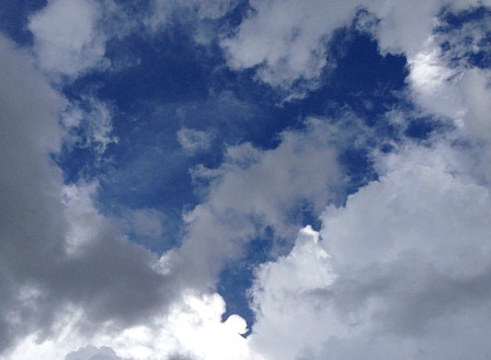 Deep blue sky shaped into a heart by white and dark clouds