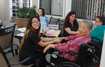 Cosmetology student performs hand massage to elderly woman.